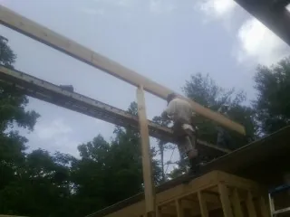 Carpenter setting a ridge beam over a new addition frame — Ice Dam Removal by Roofing Brothers in Townsville