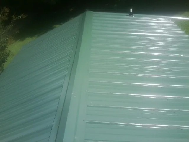 New green metal panels meeting at the ridge of a roof — Flat Roof Repair work by our crew in Townsville