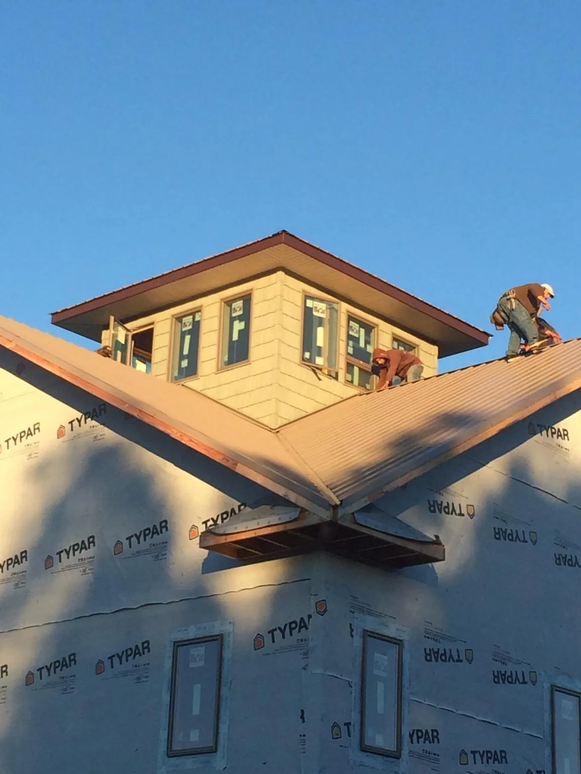 Roofers working around a rooftop cupola on a new metal roof at sunset — Roof Waterproofing in Townsville by Roofing Brothers